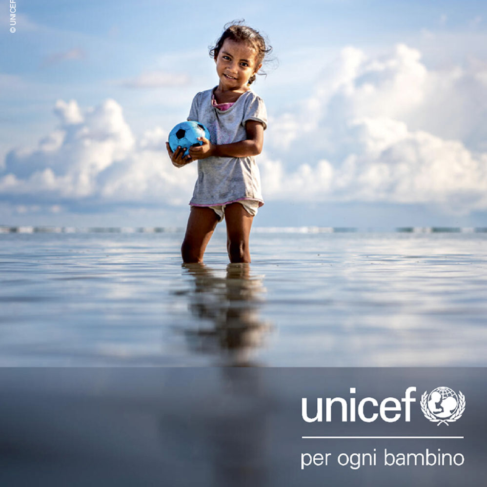 Bambina in riva al mare con il logo UNICEF